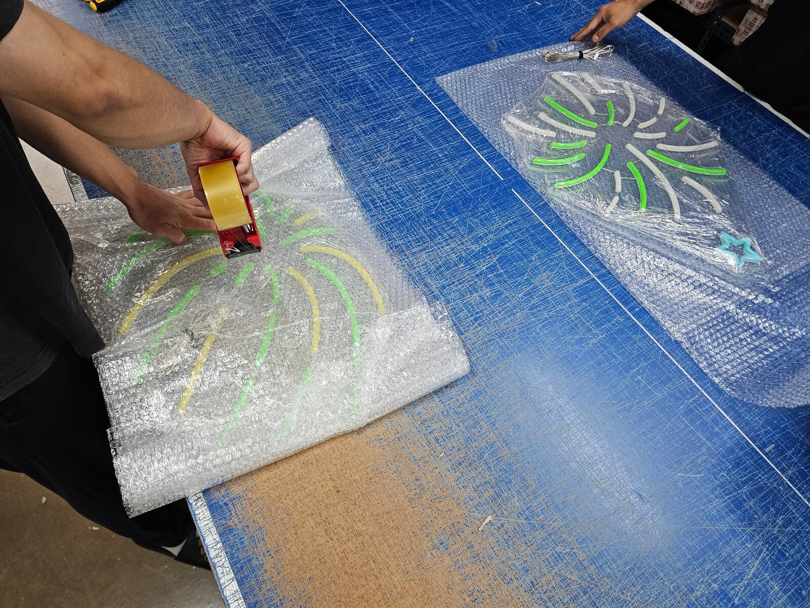 エアキャップによるネオンサインの梱包作業